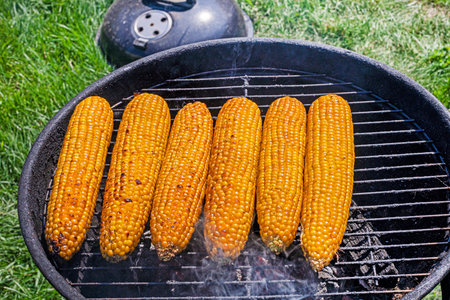 cooking sweet corn on the grill on a barbecue on a sunny day. Healthy vegan food