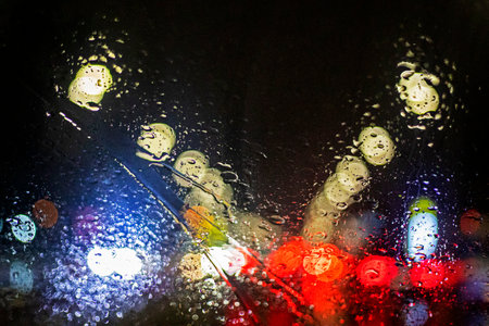 reflections of red brake lights from a car windshield in heavy rain and snow in a traffic jam. Road safety. Poor visibilityの写真素材