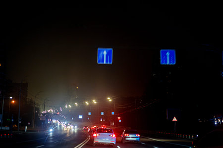 night 6-lane highway illuminated by lanterns with cars in Kyiv during the war
