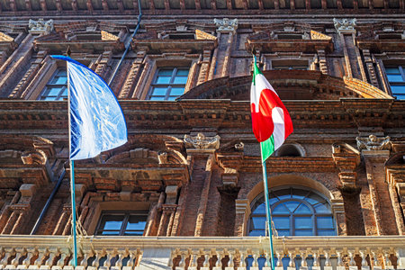 Italian flag and NATO flag on an old building on a sunny day in Milan, Italyの写真素材