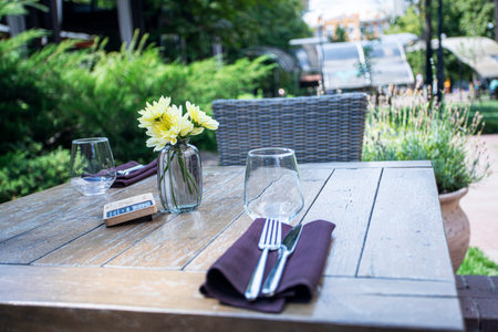 yellow chrysanthemums in a small vase on a table in a cafe outsideの写真素材