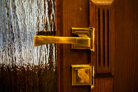 gilded handle with a stripped lock on a wooden door with glass windowsの写真素材