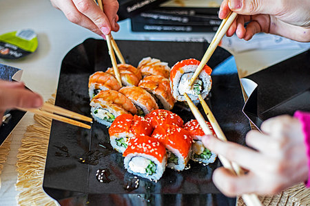 family eats sushi rolls set with chopsticks. festive evening in japanese styleの写真素材