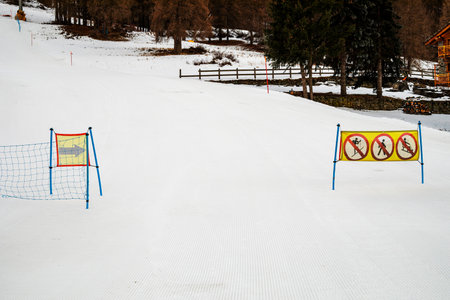 end of ski run fenced with safety net and prohibitory signs at Italian resort in the Alpsの写真素材