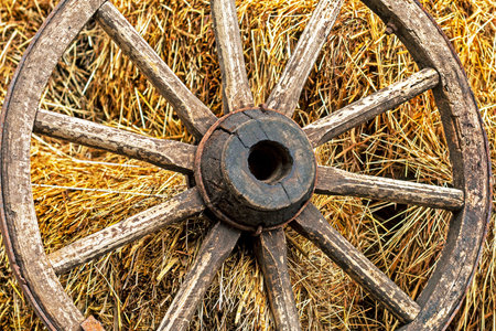 old wooden cart wheel on a straw background. Country style in the interior