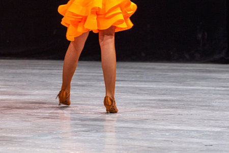 junior girl in a bright orange Latin American dress before the qualifying tournament. Ballroom dancingの写真素材
