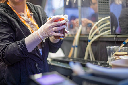 sell in a disposable transparent plastic cup of recyclable materials chilled drink beer or kvass in gloves. street foodの写真素材