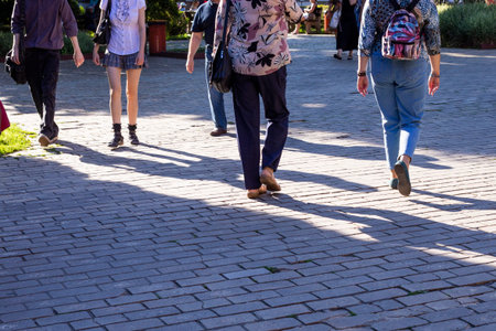 legs of passers-by on a city square on a sunny day