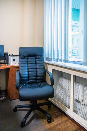 black stylish leather computer chair in the office near the windowの写真素材