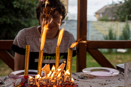 happy boy celebrates his 14th birthday with sparklers outdoors. Teenage period features