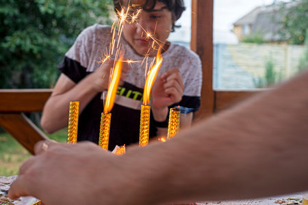 boy celebrates his 14th birthday with sparklers outdoors. Peculiarities of adolescenceの写真素材