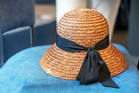 women's hat tied with ribbon on a blue chair. Weekend, soon on vacation