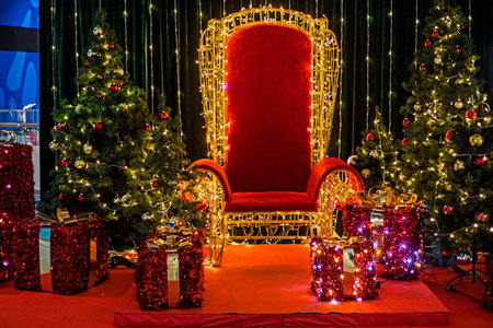 decorative red gold chair with Christmas trees and festive wrapped gifts with glowing lanterns.の写真素材