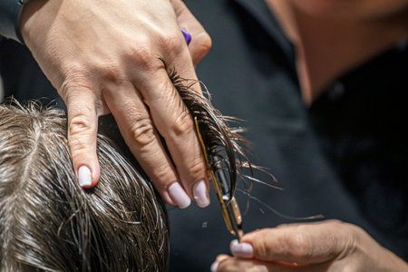 stylist creates a stylish haircut under a comb removing excess hairの写真素材