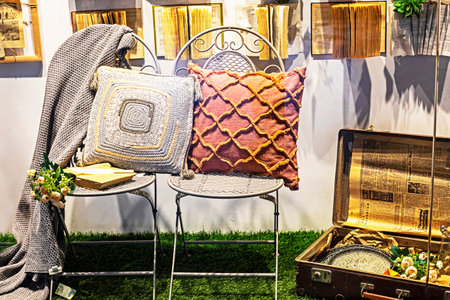 Stylish interior with books, flower vase, chairs, and sofa cushionsの写真素材