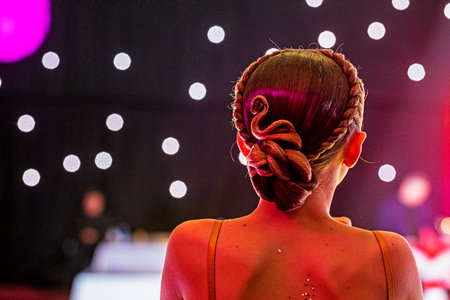 back of a young dancer's beautiful curled hairstyle at a tournamentの写真素材