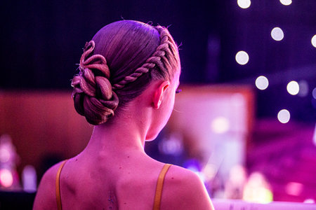 back of a young dancer's beautiful curled hairstyle at a tournamentの写真素材