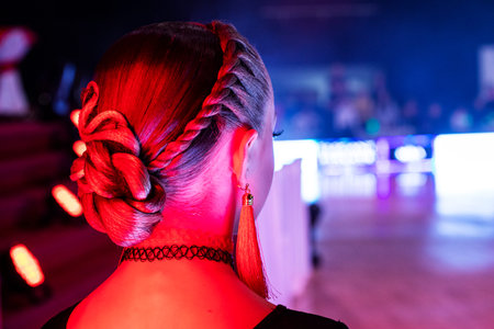 young dancer's beautiful bun hairstyle for a dance tournament with red earrings.