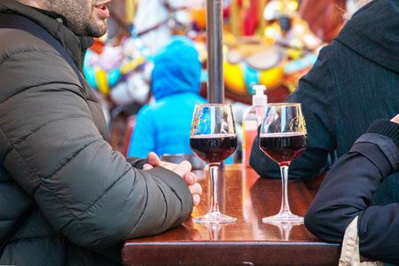 Drinking and socializing over glasses of punch or red wine at a table at an outdoor fair.の写真素材