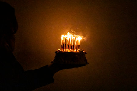 Blowing out candles on a birthday cake in the dark. Birthday and partyの写真素材