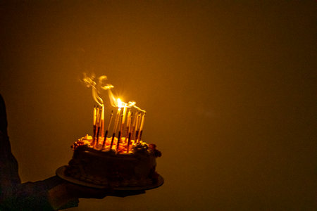Blowing out candles on a birthday cake in the dark. Birthday and partyの写真素材