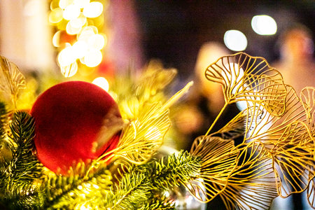 Decorative ornaments on a Christmas tree illuminated with garlandsの写真素材