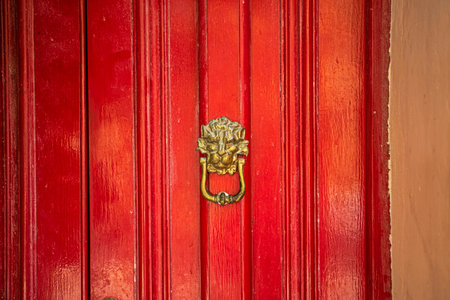 red wooden door with a gilded lion's head handle. Traveling in Europeの写真素材