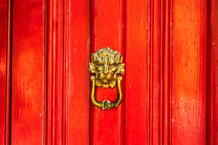 red wooden door with a gilded lion's head handle. Traveling in Europeの写真素材