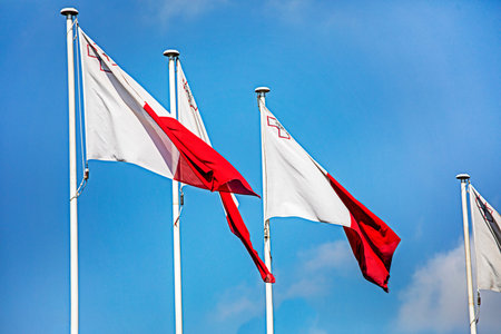 Malta flags on a flagpole against the sky. Traveling in Europe