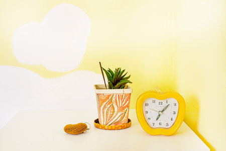 clock with a houseplant and a heart in a yellow bedroom. Seasonal Clock Change