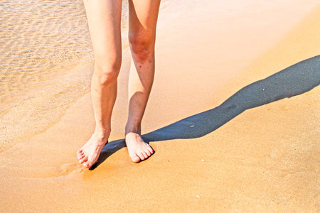 Women's feet on wet sand at the beach. Joint and skin health