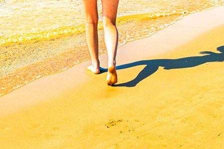 Women's feet walking on wet sand on the beach. Joint and skin healthの写真素材