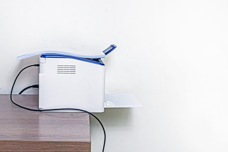 A printer on an office desk with a stack of paper on top.