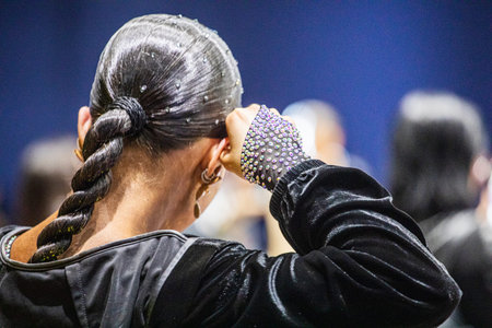 A dancer adjusts her ponytail before a dance competition