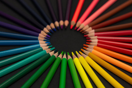 Vibrant colored pencils arranged in perfect circle in the center on dark background. Creative concept symbolizing art, design, education, diversity, innovation, and color harmony. Modern minimal flat lay composition with copy space.の写真素材