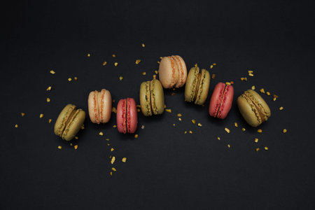 Close-up flat lay of seven pastel colored French macarons arranged in the center with pistachio...