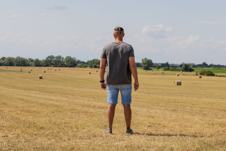 The man stay in agriculture field and looking away into the distance.の写真素材
