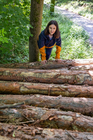Woman tourist climbs up the wooden logs in the forest.の写真素材