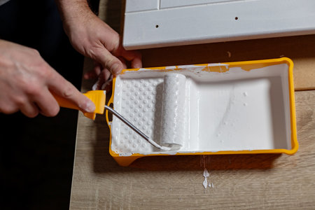 DIY home improvement project underway with a person painting a wall using a rollerの写真素材