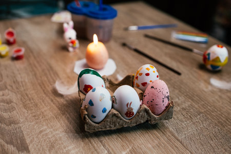Colorful decorated eggs arranged in an egg carton on a wooden table during springtime festivitiesの写真素材