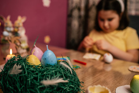Child enjoys decorating Easter eggs with colorful materials at home during spring afternoon