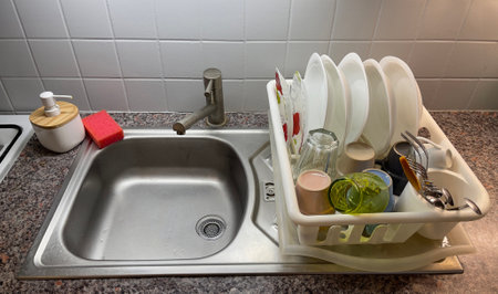 Kitchen sink area with neatly arranged drying dishes and utensils on a countertopの写真素材
