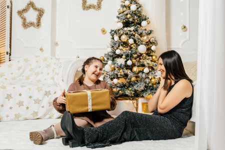 Joyful moments shared as a girl receives a gift from her mother during a cozy holiday celebration at homeの写真素材