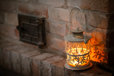 white lantern on a shelf near the fireplace against a brick wall  beautiful Christmas card の写真素材