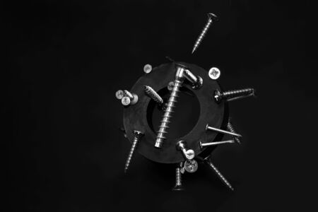 Metal chrome screws, nails and a Magnet fly in the air, isolated on a dark background. The concept of object levitation. Demonstration of magnetism.Selective focus. Copy space.Macro modeの写真素材
