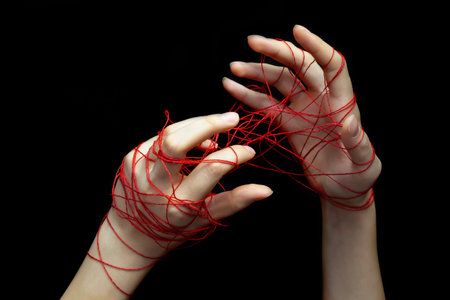 Two female hands entangled in a network of red social media threads on a black isolated...