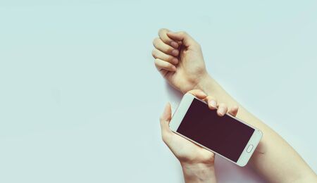 A womans hand holds a mobile phone like a syringe with an injection needle. Light blue background, copy space, banner, selective focus.The concept of social dependenceの写真素材