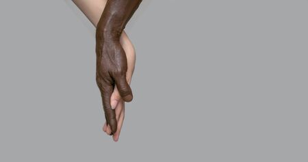 Black male and white female human hands touch palms, holding each other. The concept of inter-racial friendship and respect, the fight against racism. Banner, copy of space, gray isolated backgroundの写真素材