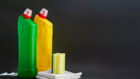 Household sponge, two white rags, two plastic bottles for liquid household chemicals: yellow, green...