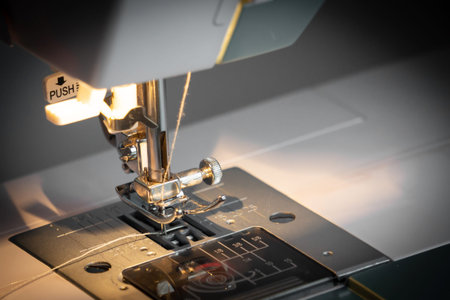 Close-up of a sewing machine and a sewing needle in the light of an incandescent lamp. The concept...